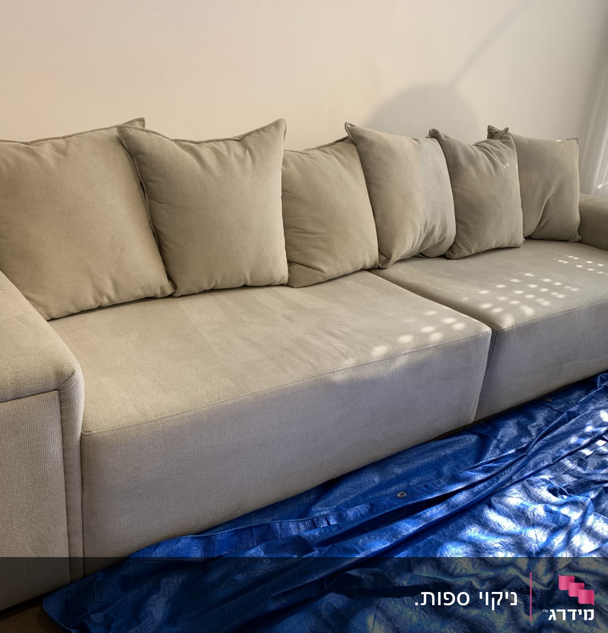 ספה אפורה עם כיסוי מגן כחול על הרצפה